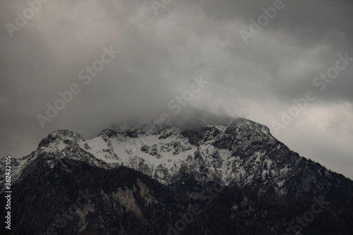 moody dramatic mountain landscape cloudy gray weather day time with Alps mountains snowy peak range