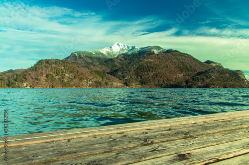 north Europe spring time landscape with mountain snowy peak background scenic view lake waters and wooden pier foreground