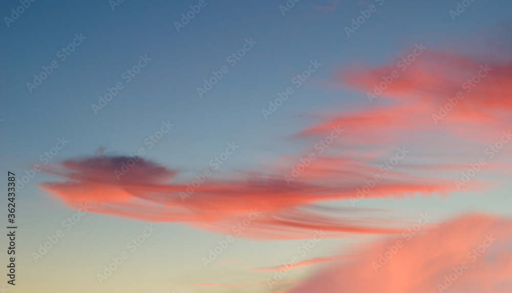 Naklejka premium Nuvens no céu azul ao por do sol com tons de cores vermelhas