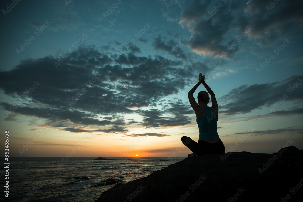 Yoga woman exercise on the ocean coast at twilight.