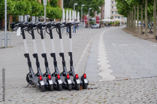 Selected focus at Group E-scooter or Electric Scooter by startup company with concept of Eco friendly mobility urban lifestyle, park on promenade along riverside of Rhine River in Düsseldorf, Germany.