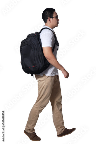 Full length portrait of Asian man wearing white shirt, khaki jeans and backpack standing walking, side view