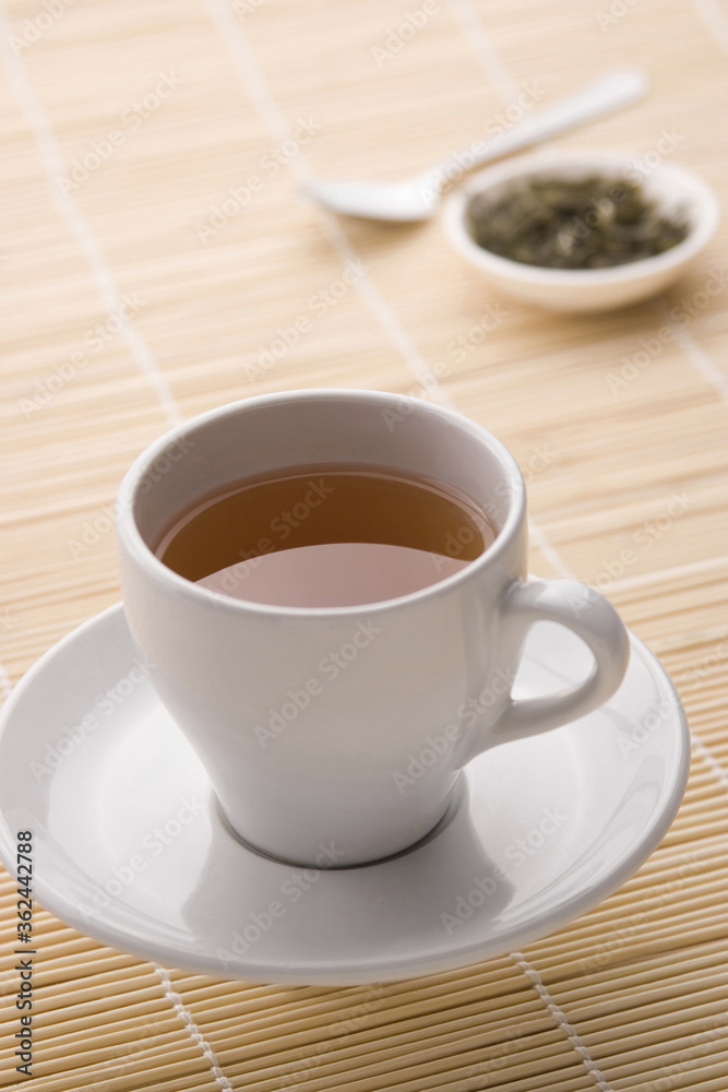 A cup of tea with tea leaves in the background A cup of tea with tea leaves in the background