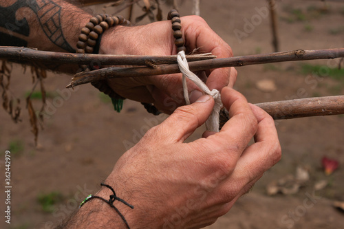 Foto Manos atando un nudo en los palos para un temazcal