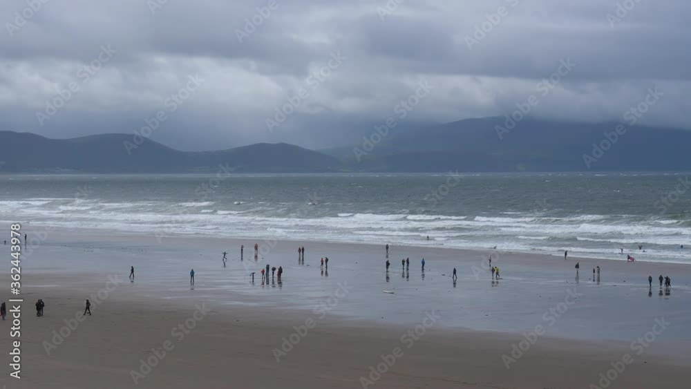 Panoramic view of distant people on the Inch beach of Dingle peninsula in a bad weather, Republic of Ireland. Panoramic view of distant people on the Inch beach of Dingle peninsula in a bad weather, Republic of Ireland.