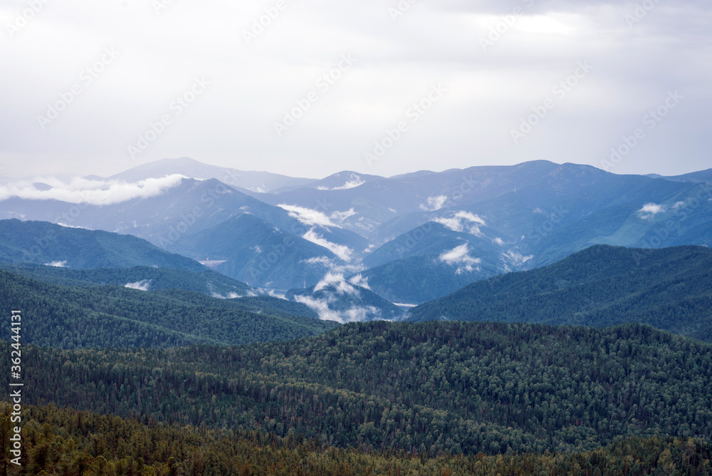 Sayan mountains view after rain. Low clouds and rain clouds