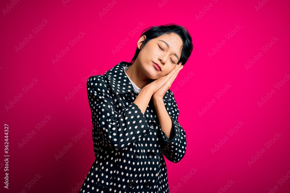 Young beautiful asian girl wearing casual jacket standing over isolated pink background sleeping tired dreaming and posing with hands together while smiling with closed eyes.