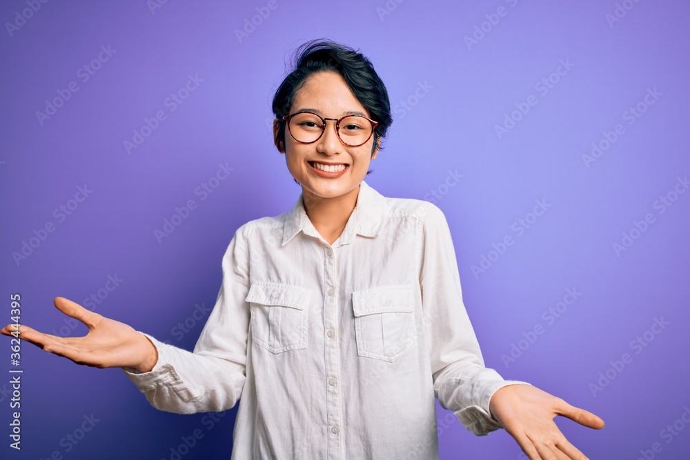 Young beautiful asian girl wearing casual shirt and glasses standing over purple background smiling cheerful with open arms as friendly welcome, positive and confident greetings Young beautiful asian girl wearing casual shirt and glasses standing over purple background smiling cheerful with open arms as friendly welcome, positive and confident greetings