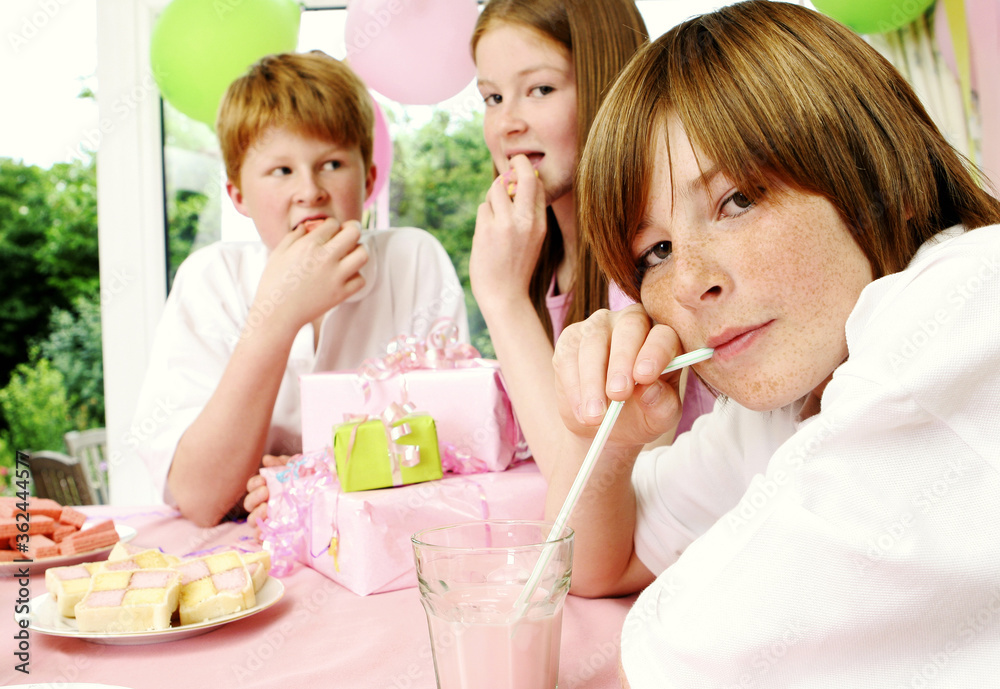 A girl and her two brothers sitting together enjoying the food and drinks A girl and her two brothers sitting together enjoying the food and drinks