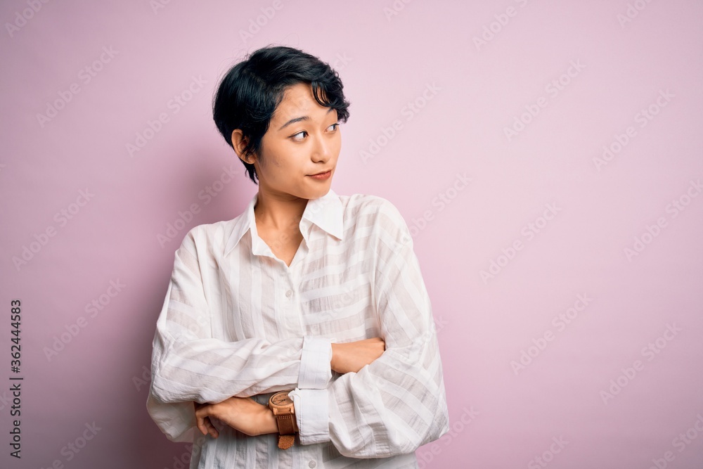 Young beautiful asian girl wearing casual shirt standing over isolated pink background looking to the side with arms crossed convinced and confident Young beautiful asian girl wearing casual shirt standing over isolated pink background looking to the side with arms crossed convinced and confident