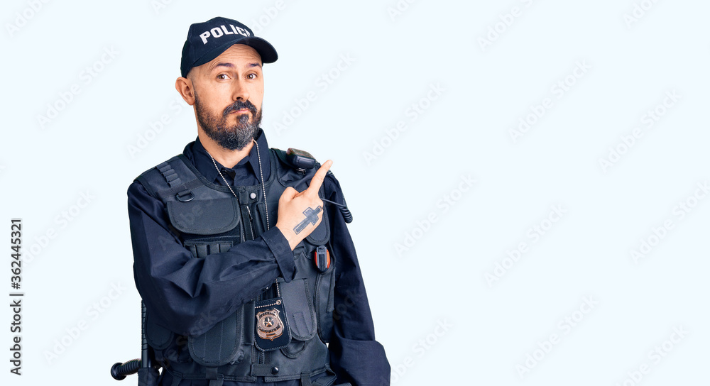 Young handsome man wearing police uniform pointing with hand finger to the side showing advertisement, serious and calm face Young handsome man wearing police uniform pointing with hand finger to the side showing advertisement, serious and calm face