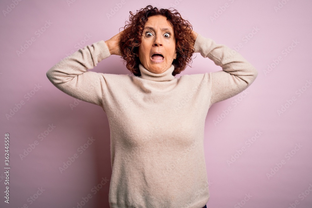 Middle age beautiful curly hair woman wearing casual turtleneck sweater over pink background Crazy and scared with hands on head, afraid and surprised of shock with open mouth Middle age beautiful curly hair woman wearing casual turtleneck sweater over pink background Crazy and scared with hands on head, afraid and surprised of shock with open mouth