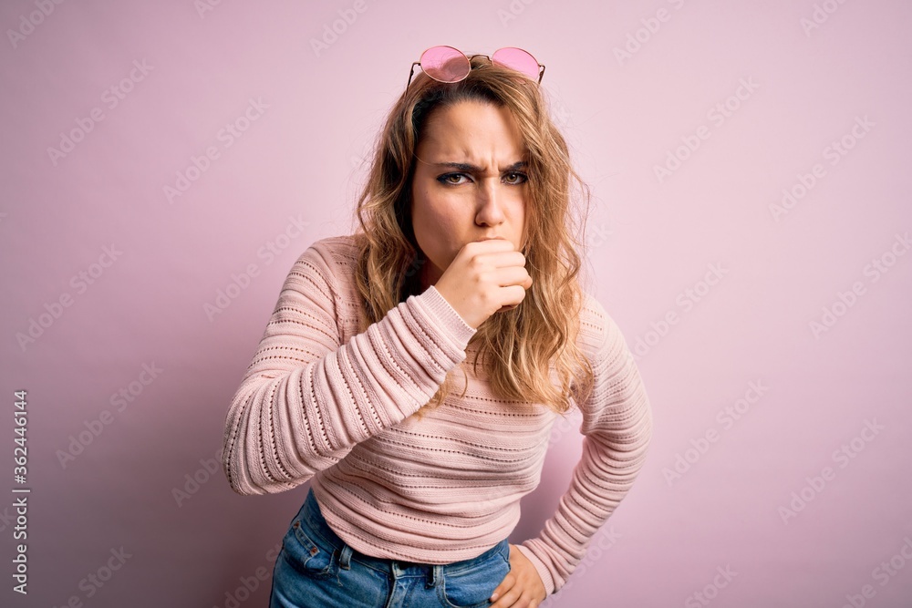 Young beautiful blonde woman wearing casual sweater and sunglasses over pink background feeling unwell and coughing as symptom for cold or bronchitis. Health care concept. Young beautiful blonde woman wearing casual sweater and sunglasses over pink background feeling unwell and coughing as symptom for cold or bronchitis. Health care concept.