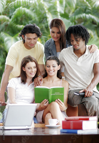 Three ladies, a guy and an African American guy sharing a book