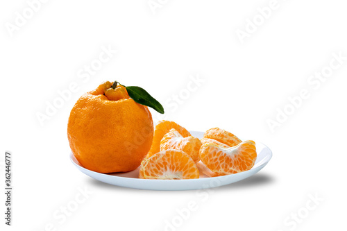 Whole Ponkan tangerine and one peeled in segments on a plate isolated on white background. photo