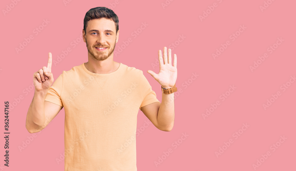 Handsome young man with bear wearing casual yellow tshirt showing and pointing up with fingers number six while smiling confident and happy. Handsome young man with bear wearing casual yellow tshirt showing and pointing up with fingers number six while smiling confident and happy.