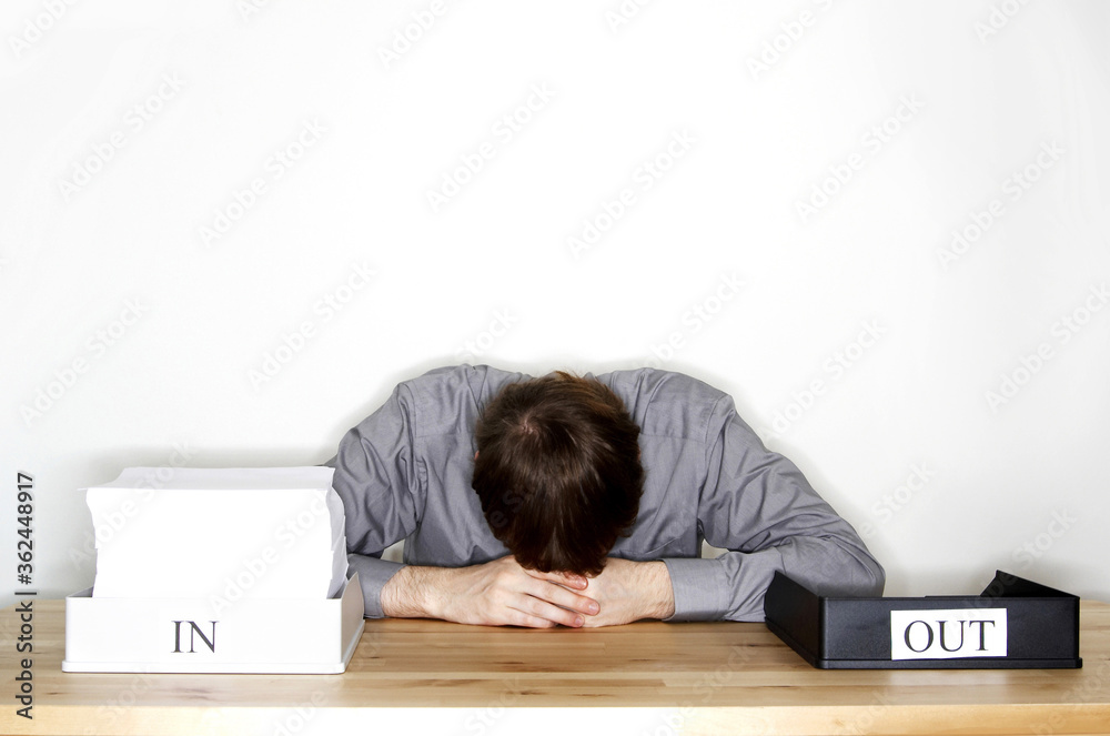 A man feeling stressful with the stack of paperwork he has to do A man feeling stressful with the stack of paperwork he has to do