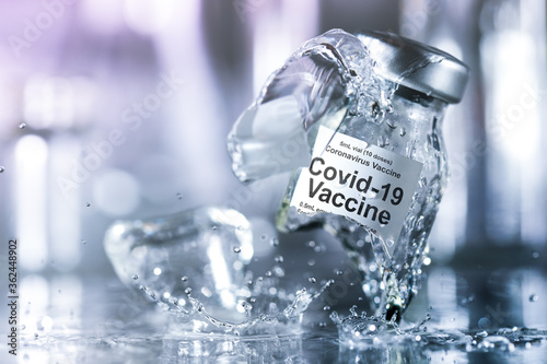 Coronavirus vaccine vial breaking into pieces with splashing liquid. Failure to create a vaccine, find a cure for the corona virus, or the dangers of an untested drug concept. photo