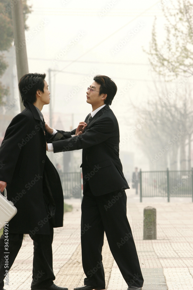 Two guys in business suit pushing each other