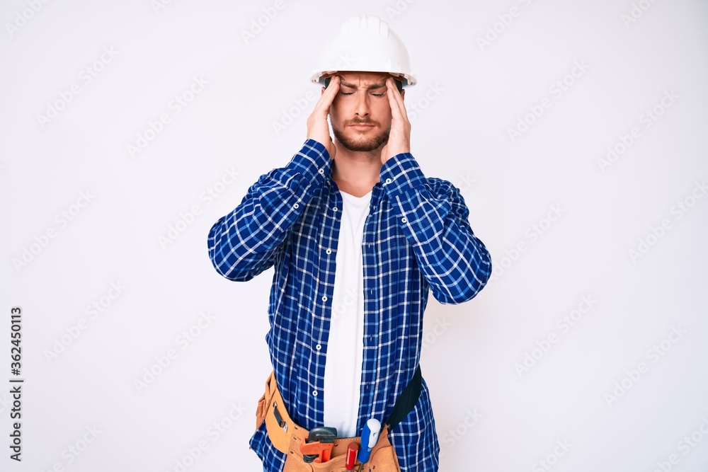Young handsome man weaing handyman uniform suffering from headache desperate and stressed because pain and migraine. hands on head. Young handsome man weaing handyman uniform suffering from headache desperate and stressed because pain and migraine. hands on head.