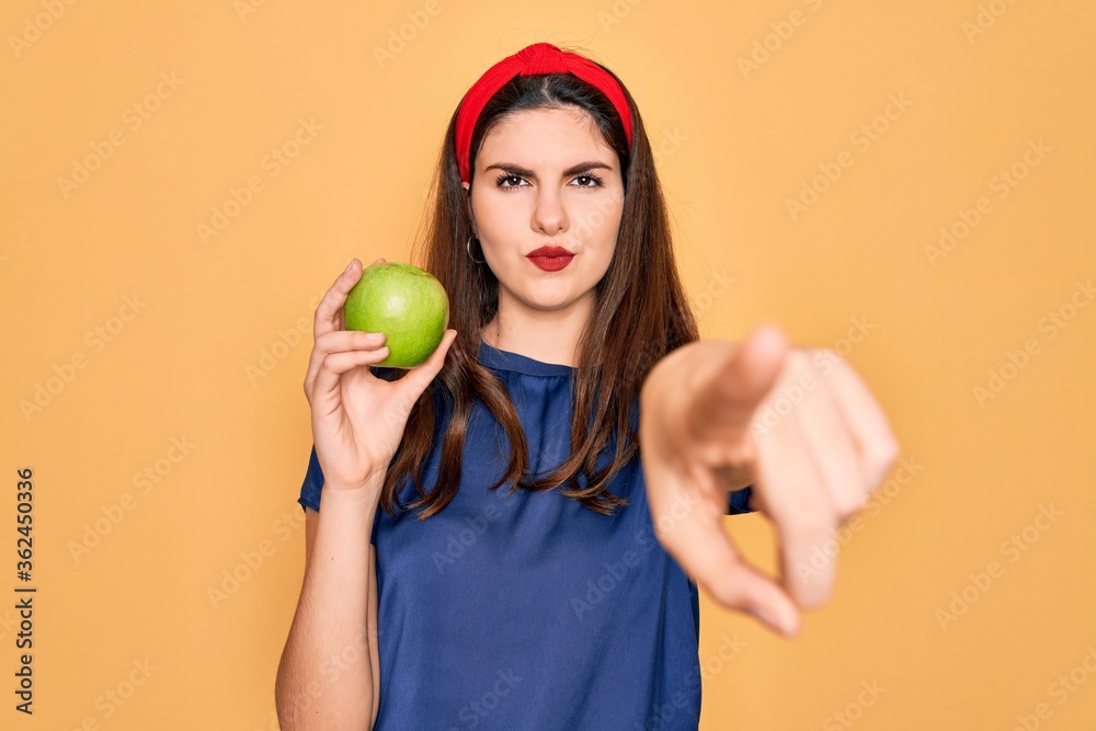 Φωτογραφία Young beautiful girl eating fresh organic healthy green apple over yellow backgr