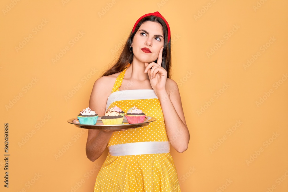 Φωτογραφία Young beautiful pin up woman wearing 50s fashion vintage dress holding tray with