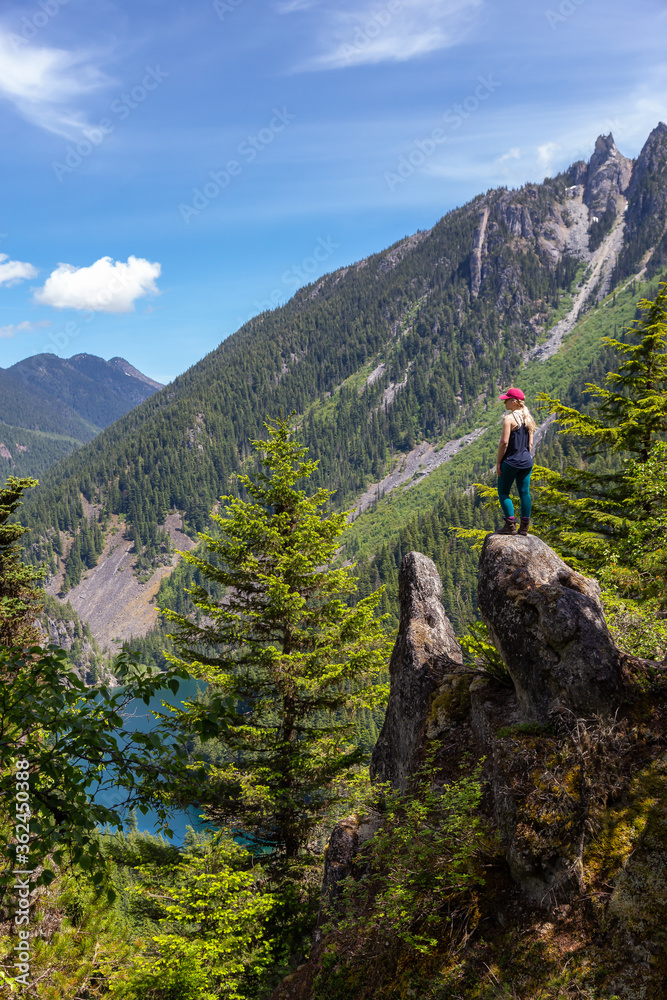 Girl on Top of Cliff with Beautiful View of Canadian Mountain Landscape during a vibrant sunny day. Taken on a Hike to Goat Ridge in Chilliwack, East of Vancouver, British Columbia, Canada.