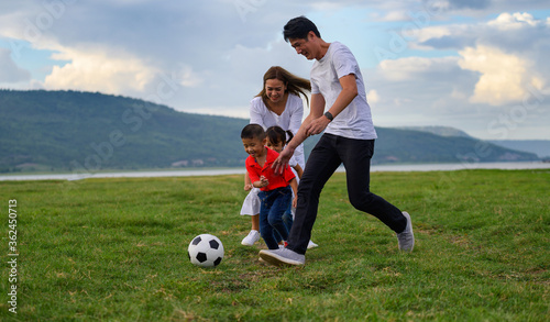 Cheerful family Asian playing football in a green lawn © PK Studio
