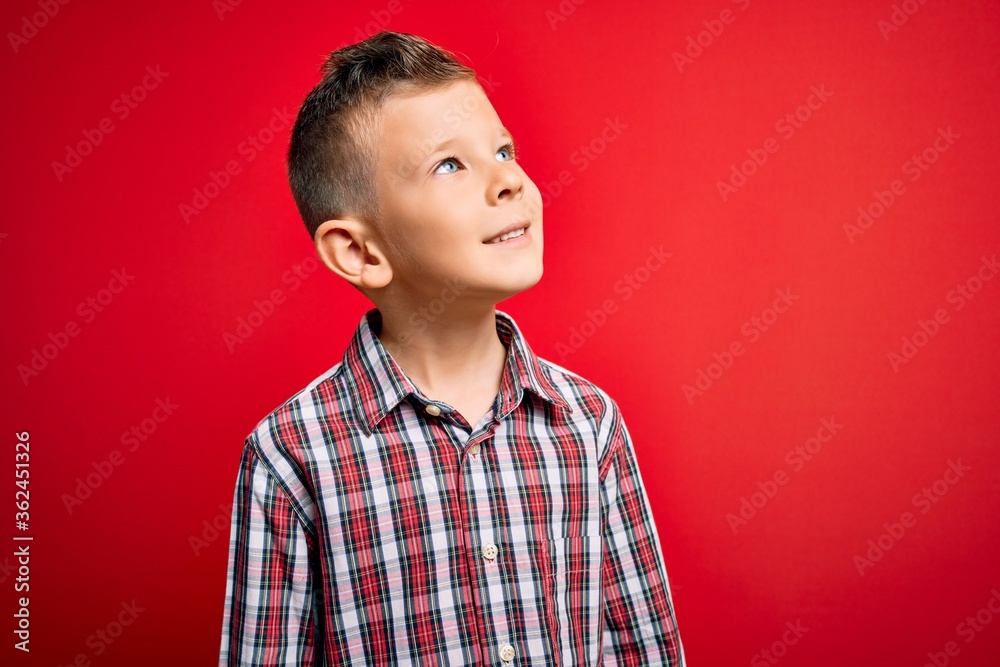 Young little caucasian kid with blue eyes standing wearing elegant shirt over red background looking away to side with smile on face, natural expression. Laughing confident. Young little caucasian kid with blue eyes standing wearing elegant shirt over red background looking away to side with smile on face, natural expression. Laughing confident.