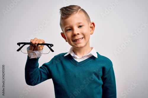 Young little caucasian kid holding eyesight glasses correction over isolated background with a happy face standing and smiling with a confident smile showing teeth photo