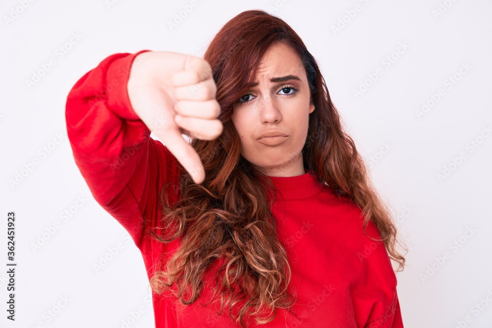 Young beautiful woman wearing casual clothes looking unhappy and angry showing rejection and negative with thumbs down gesture. bad expression. Young beautiful woman wearing casual clothes looking unhappy and angry showing rejection and negative with thumbs down gesture. bad expression.