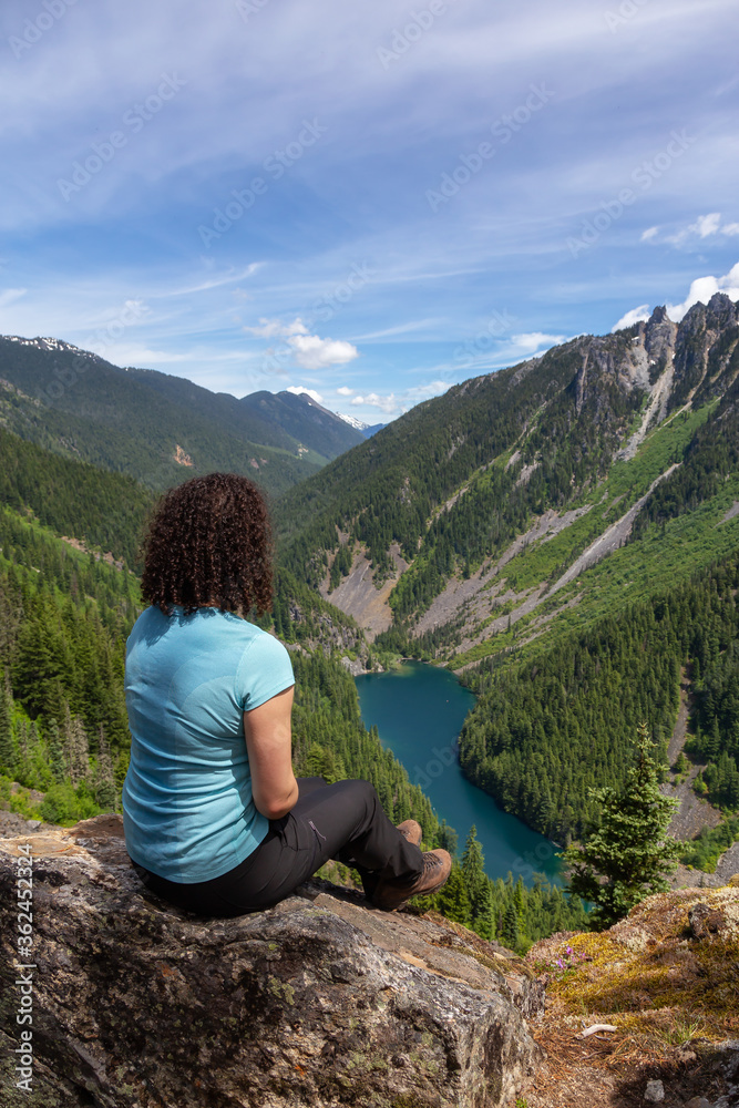 Girl on Top of Cliff with Beautiful View of Canadian Mountain Landscape during a vibrant sunny day. Taken on a Hike to Goat Ridge in Chilliwack, East of Vancouver, British Columbia, Canada.