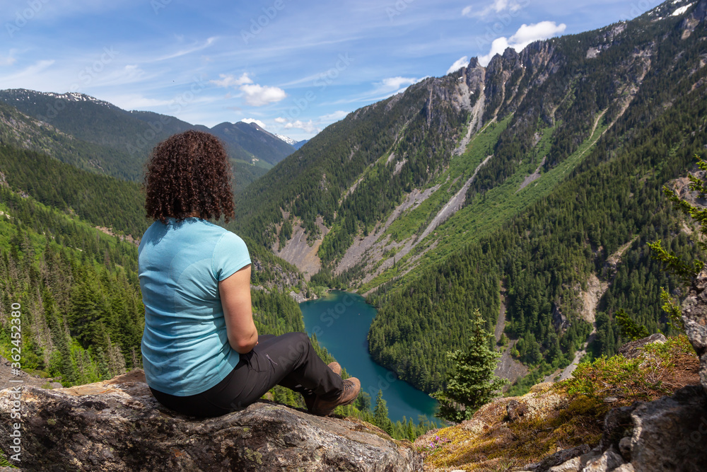 Girl on Top of Cliff with Beautiful View of Canadian Mountain Landscape during a vibrant sunny day. Taken on a Hike to Goat Ridge in Chilliwack, East of Vancouver, British Columbia, Canada.