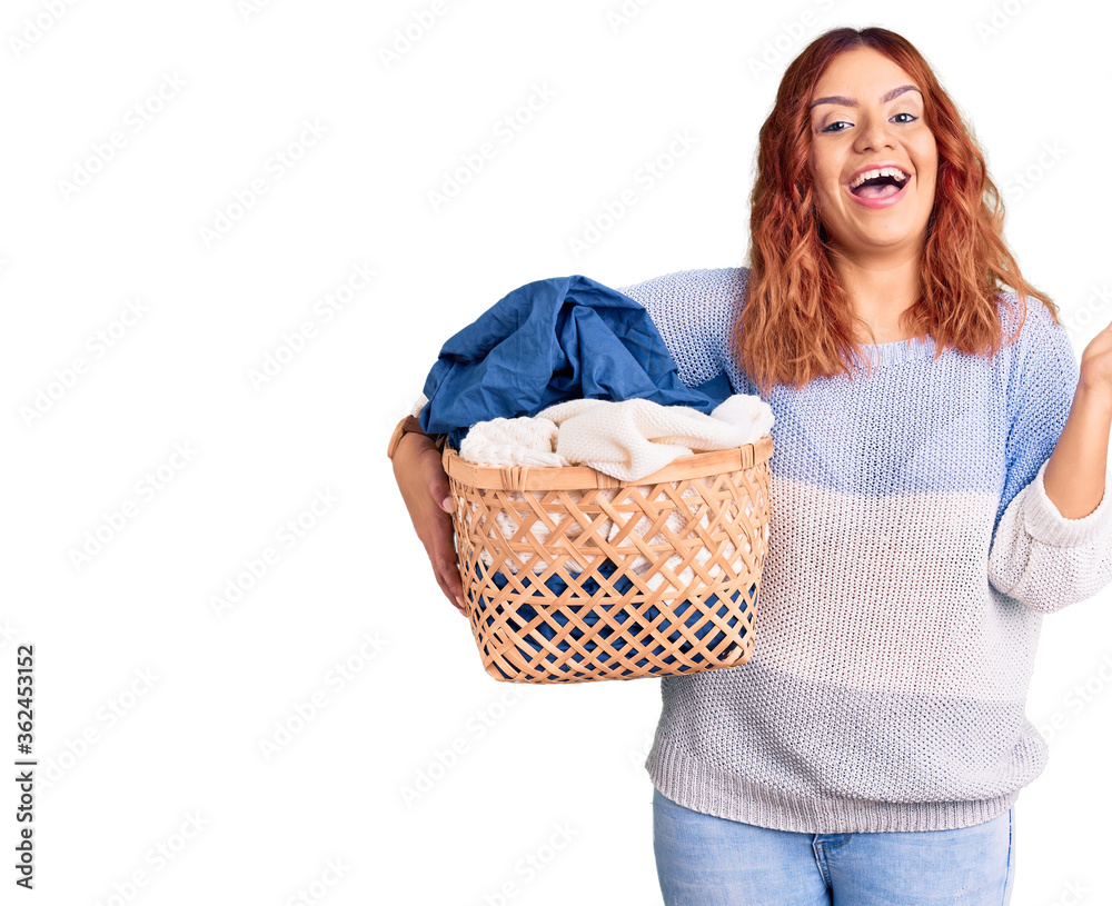 Young latin woman holding laundry basket celebrating victory with happy smile and winner expression with raised hands Young latin woman holding laundry basket celebrating victory with happy smile and winner expression with raised hands