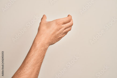 Hand of caucasian young man showing fingers over isolated white background holding invisible object, empty hand doing clipping and grabbing gesture