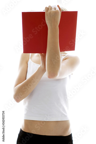 Fototapeta A lady in white camisole holding up a book covering her face