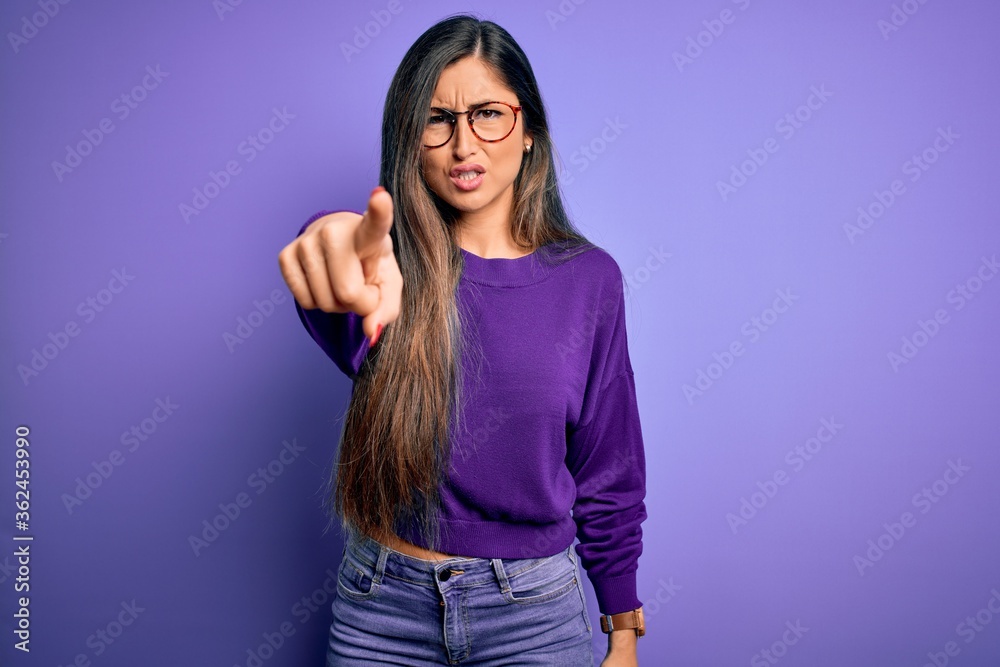 Young beautiful smart woman wearing glasses over purple isolated background pointing displeased and frustrated to the camera, angry and furious with you Young beautiful smart woman wearing glasses over purple isolated background pointing displeased and frustrated to the camera, angry and furious with you