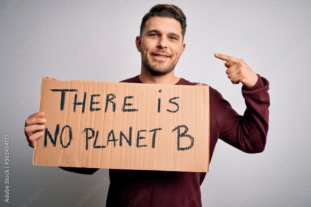 Young activist man holding protest banner for climate change and environment change with surprise face pointing finger to himself