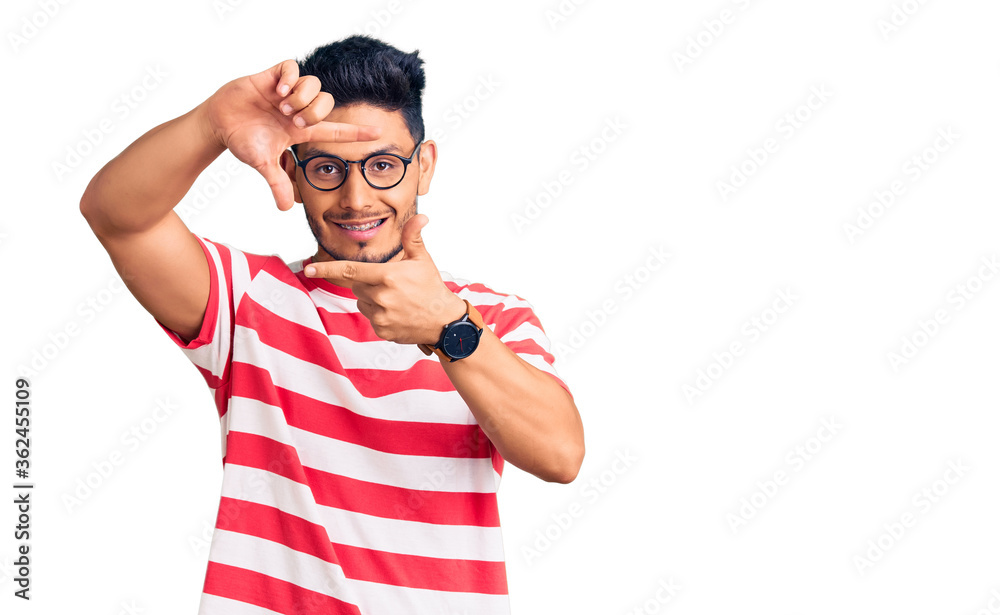 Handsome latin american young man wearing casual clothes and glasses smiling making frame with hands and fingers with happy face. creativity and photography concept. Handsome latin american young man wearing casual clothes and glasses smiling making frame with hands and fingers with happy face. creativity and photography concept.