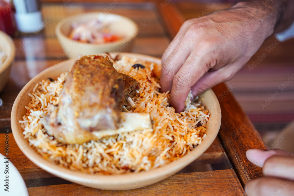 Man eating using hand a traditional biryani rice and chicken dish in local restaurant