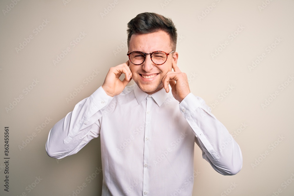 Young handsome business mas wearing glasses and elegant shirt over isolated background covering ears with fingers with annoyed expression for the noise of loud music. Deaf concept. Young handsome business mas wearing glasses and elegant shirt over isolated background covering ears with fingers with annoyed expression for the noise of loud music. Deaf concept.
