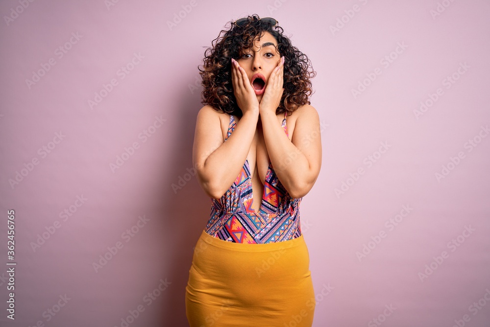 Young beautiful arab woman on vacation wearing swimsuit and sunglasses over pink background afraid and shocked, surprise and amazed expression with hands on face Young beautiful arab woman on vacation wearing swimsuit and sunglasses over pink background afraid and shocked, surprise and amazed expression with hands on face