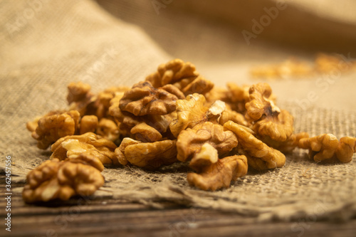 Peeled walnuts in bulk on a wooden table covered with rough-textured burlap. Healthy diet. Fitness diet. Close up.