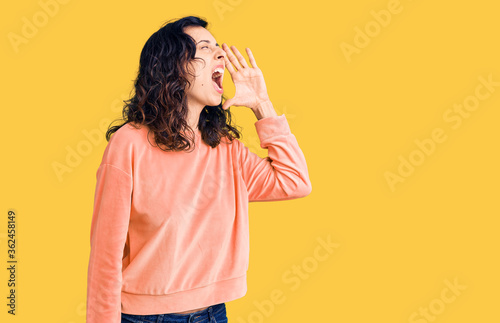 Young beautiful hispanic woman wearing casual clothes shouting and screaming loud to side with hand on mouth. communication concept.
