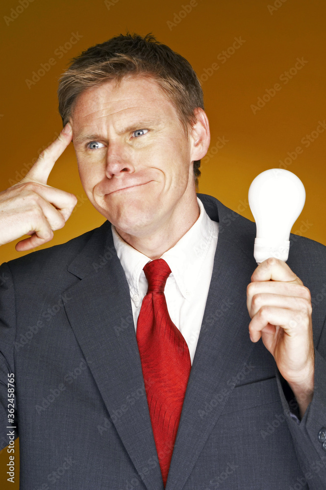 Businessman thinking while holding a light bulb Businessman thinking while holding a light bulb