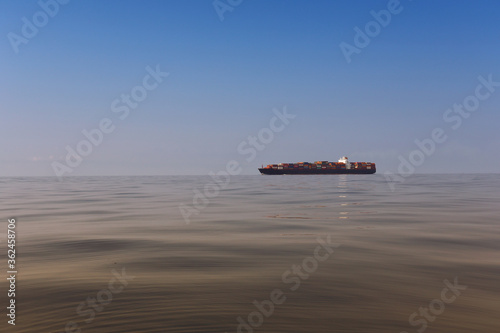 Cargo ship on the morning sea in a clear day and clear sky.