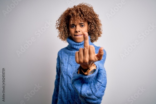 Young beautiful african american woman wearing turtleneck sweater over white background Showing middle finger, impolite and rude fuck off expression