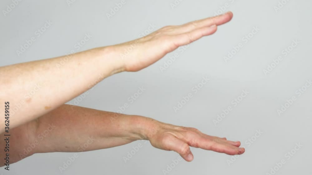 A senior woman flutters her hands up and down demonstrating her range of motion while stretching with her palms open. A senior woman flutters her hands up and down demonstrating her range of motion while stretching with her palms open.