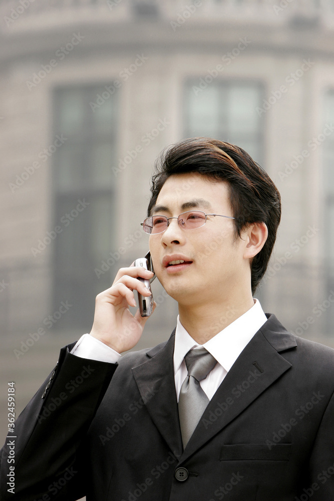 A bespectacled businessman talking on the hand phone A bespectacled businessman talking on the hand phone