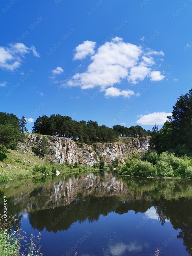 Manturov stone on Rezh river, national reserve of Ural mountains. Good view landscape, stone, forest and sky, reflection in water. Ideal for presentation about russian nature and environment